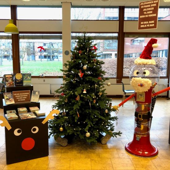 En juleudstilling på biblioteket med et juletræ, en julemand og et rensdyr 