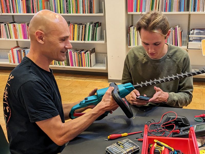 To frivillige i bibliotekets Repair Cafe reparerer en hæksaks