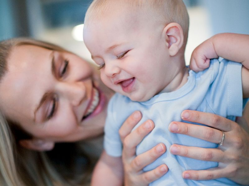 Glad mor holder smilende baby