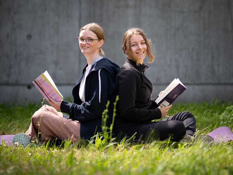 Yogainstruktør Helene Tost og litteraturformidler Mette Bjellsäter siddende ryg mod ryg