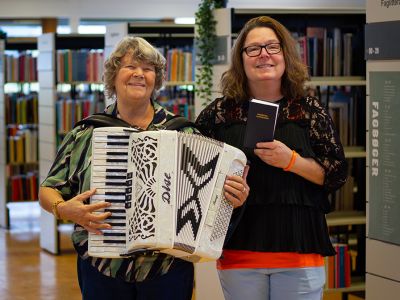 Ina Kjelstrup med harmonika og Susan Van der Klein med Højskolesangbogen