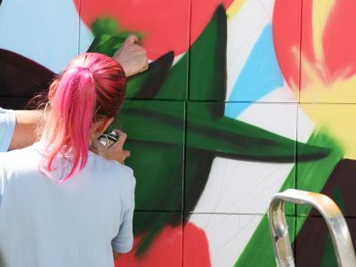 Pige og dreng maler graffiti på en væg